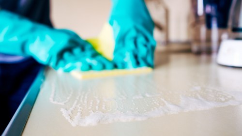 Technician applying cleaning product with safety precautions
